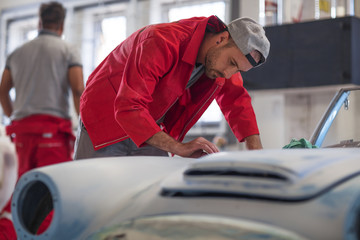 Mechanics restoring vintage cars in workshop