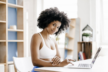 Fit young woman using laptop at home