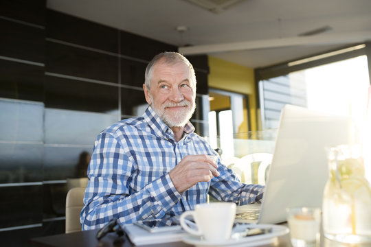 Senior businessman working on laptop in cafe