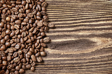 Roasted brown coffee beans on rough wooden table with blank copy space for text, top view background