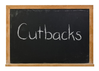 Obraz premium Cutbacks written in white chalk on a black chalkboard isolated on white