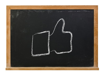 Thumbs up symbol hand drawn in white chalk on a black chalkboard isolated on white