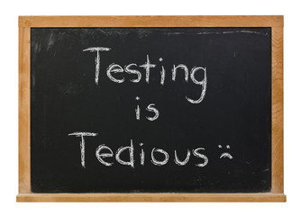 Testing is tedious written in white chalk on a black chalkboard isolated on white