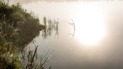 reflections in the lake water in the morning mist