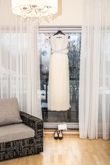 The bride's dress in light home interior in the morning of the wedding. The shoes and handbag are present.