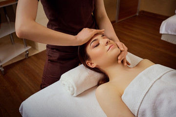 Fototapeta na wymiar Beautiful woman is given a face massage at the spa salon.