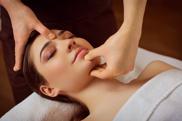 Beautiful woman is given a face massage at the spa salon.