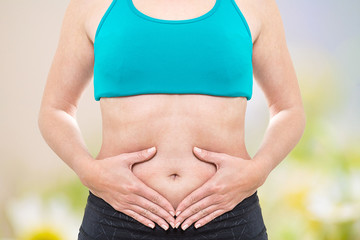 Junge Frau hält Hände auf Stress-Bauch vor Wiese