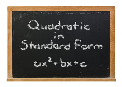 Quadratic equation in standard form written in white chalk on a black chalkboard isolated on white