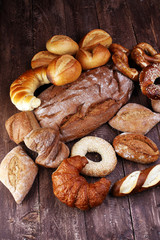 Different kinds of bread and bread rolls on board from above. Ki