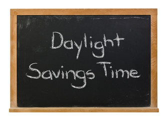 Obraz premium Daylight savings time written in white chalk on a black chalkboard isolated on white