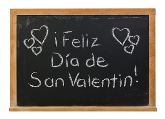 Happy Valentine's Day written in Spanish in white chalk on a black chalkboard isolated on white