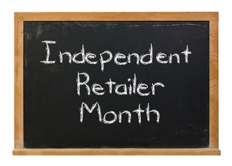 Independent retailer month written in white chalk on a black chalkboard isolated on white
