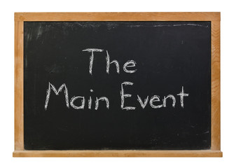 The Main Event written in white chalk on a black chalkboard isolated on white