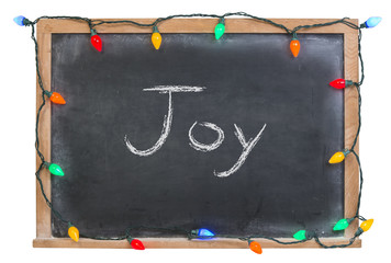 Joy written in white chalk on a black chalkboard surrounded with festive colorful lights 
isolated on white