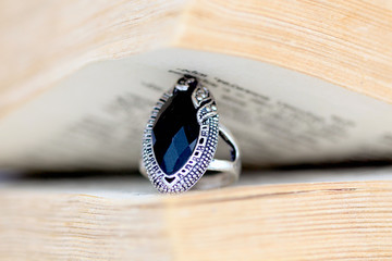 fashion ring with black gem under the pages of an old book © bellakadife