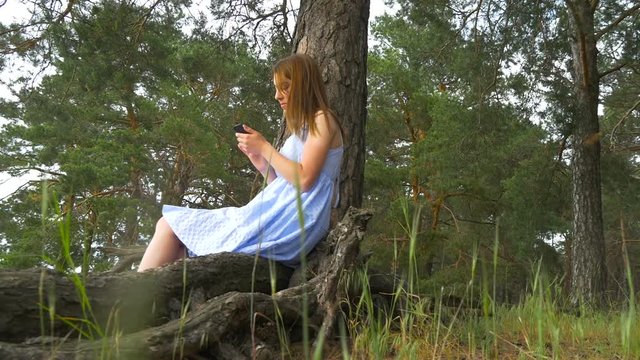 Young woman's hand touching the smartphone on the green grass - Sunset effect effect