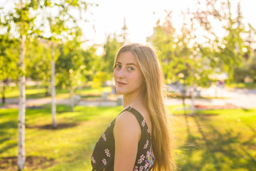 Attractive young woman enjoying her time outside in park with sunset in background