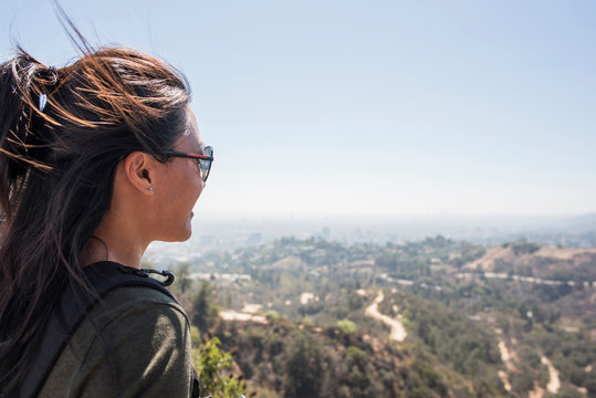 Young woman looking out at landscape from Hollywood sign, Los Angeles, California, USA