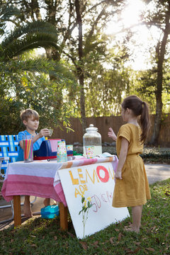 Girl buying lemonade from lemonade stand in garden