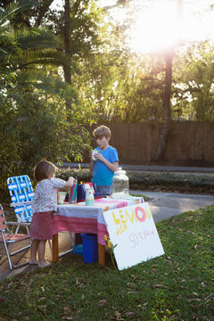 Boy and sister drinking lemonade from lemonade stand in garden