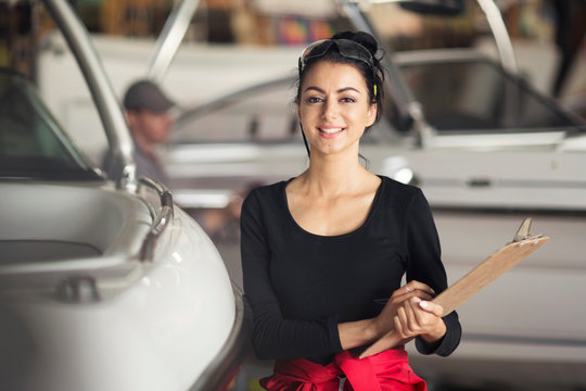 Portrait of young woman with clipboard in boat repair workshop