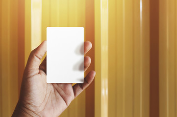 Obraz premium Hand holding Blank business card for mock up, present over yellow gold background, Warm tone filter