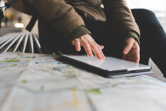 Cropped shot of female backpacker using digital tablet touchscreen on railway platform
