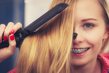 Fototapeta premium Woman straightening her long blond hair
