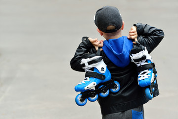 little beautiful boy with roller skates in his hands