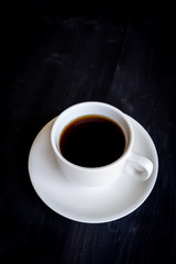 Fototapeta na wymiar Hot coffee cup on black wooden background. Favorite beverage for caffeine. Hi contrast. Food and drink background.