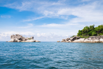 Fototapeta na wymiar Summer sea in Thailand with. Islands are under bright blue sky and a space between the islands with trees and no trees. Clouds are floating slowly above the dark blue sea. 