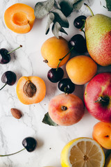 Summer fruits assorted on white marble background. Fresh raw food concept. Close up