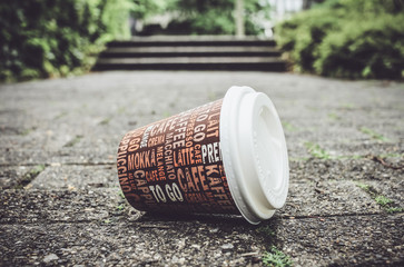 Weggeworfener leerer Kaffeebecher liegt auf Gehweg.