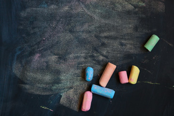 Background with colorful school chalks on a black chalkboard