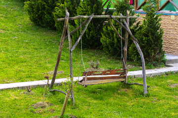 Fototapeta premium empty wooden brown swing on grass in summer