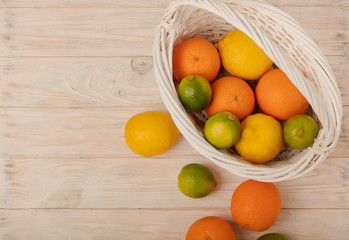 Citrus fruits - lemons, oranges and limes on a light wooden background.