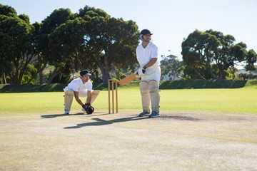 Men playing cricket at pitch against clear sky