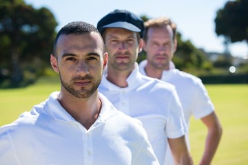 Portrait of cricket players standing at grassy field