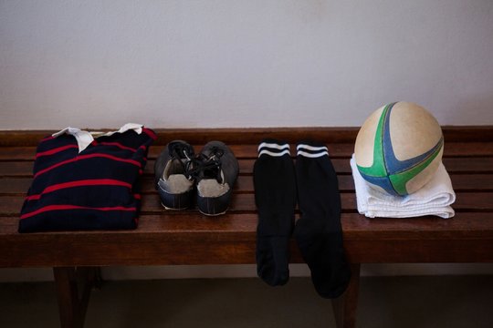 Clothes and rugby ball on wooden bench