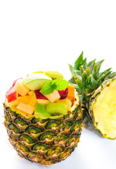 Mix tropical fruit salad in pineapple bowl, isolated white background.