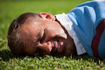 Close up of injured rugby player lying on field - Powered by Adobe