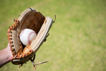 Cropped hand of baseball pitcher holding ball in glove - Powered by Adobe