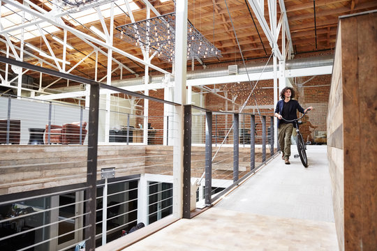 Millennial businessman walking with bike at start up office