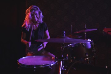 Female drummer performing on stage in nightclub