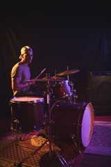 Fototapeta na wymiar Confident male performing with drum kit in nightclub