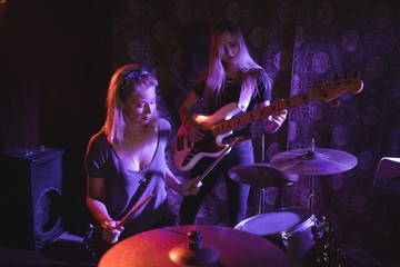 Fototapeta na wymiar Female drummer performing with guitarist in nightclub