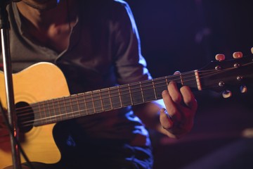 Mid section of male guitarist at music concert