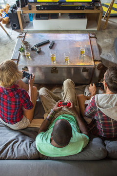 Group Of Three Friends Playing Video Games Together