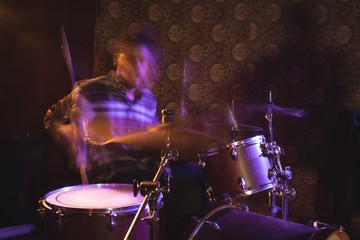 Fototapeta na wymiar Blurred motion of male drummer in nightclub